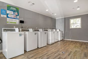 A row of washing machines are lined up in a laundry room